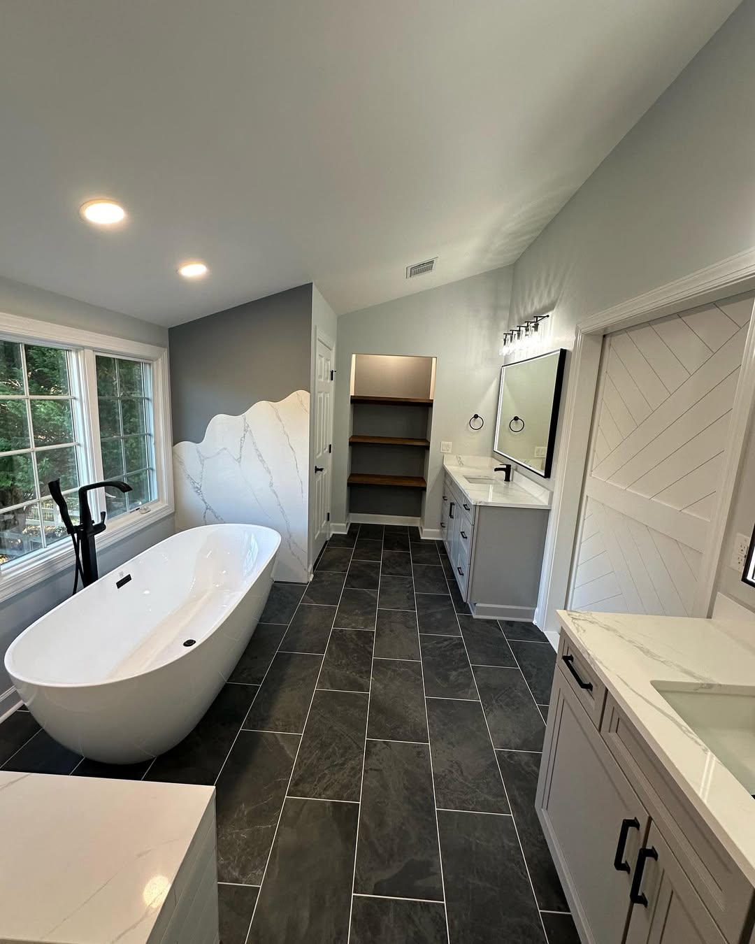 Master bathroom remodel with freestanding soaking tub, floating vanity and dark tile floor by Prime Countertops