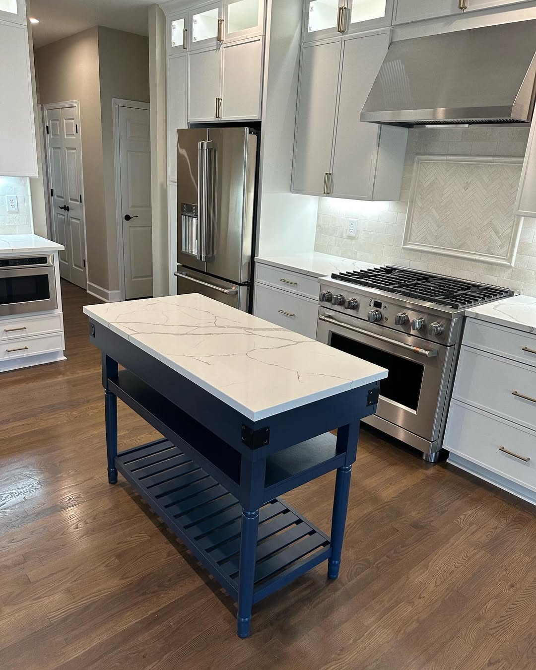 Kitchen with navy blue island, marble-look waterfall countertop and professional range by Prime Countertops