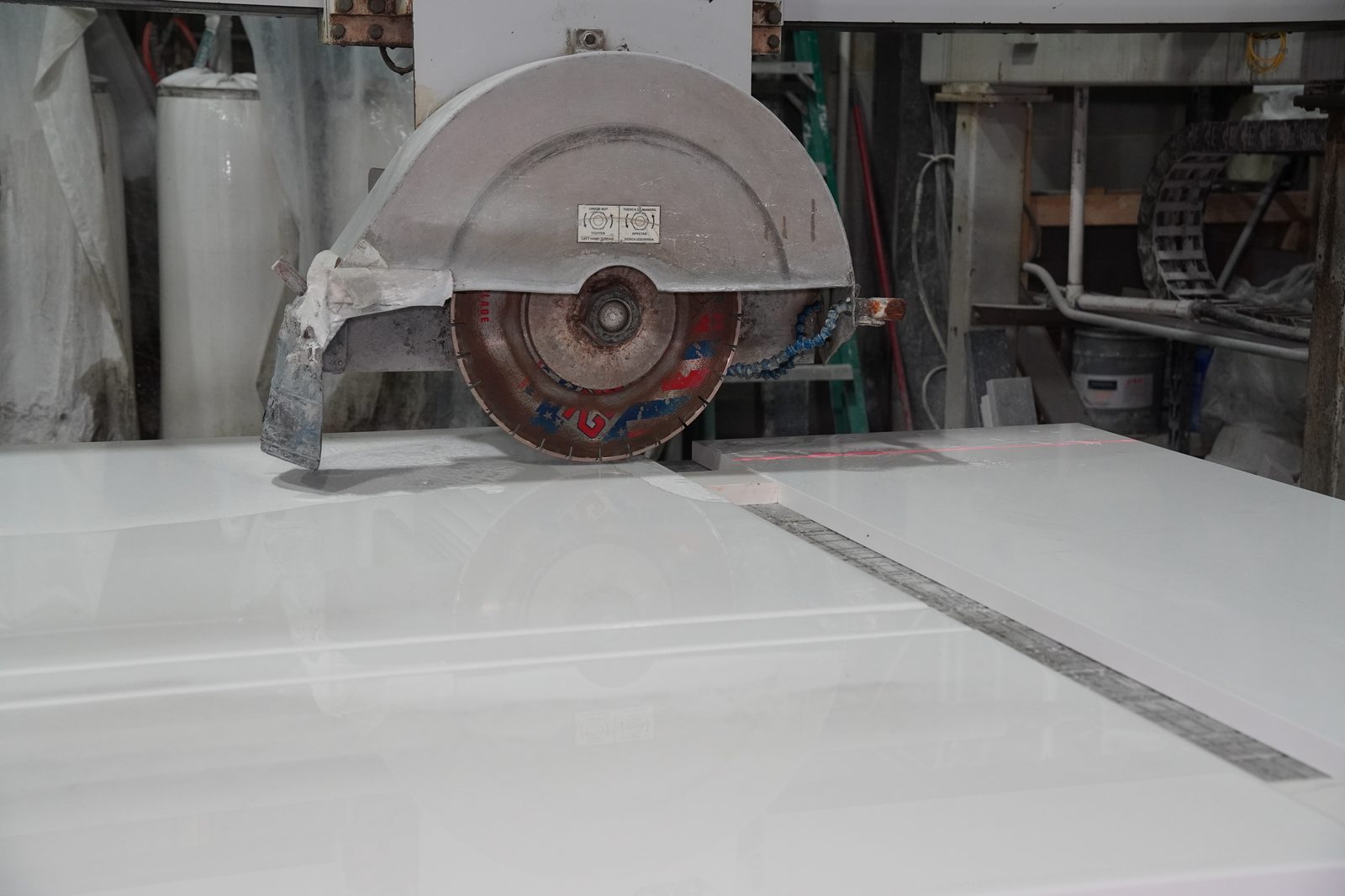 Prime Countertops fabricator cutting a stone slab on a precision bridge saw at the in-house shop