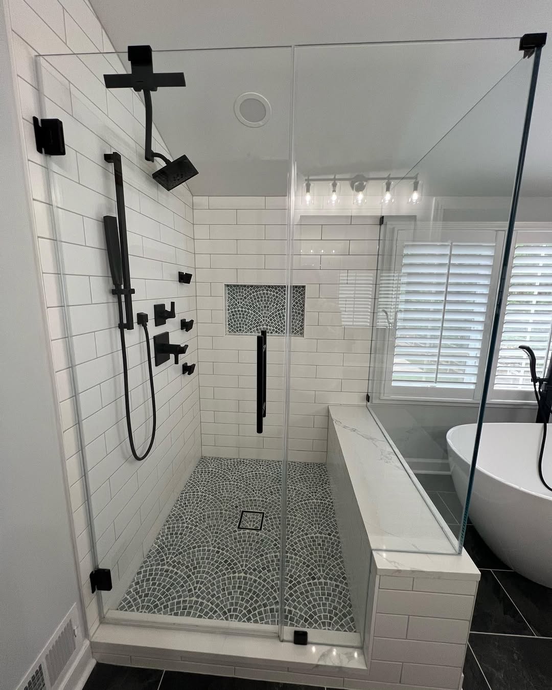 Walk-in shower with white subway tile, mosaic floor and marble-topped bench installed by Prime Countertops