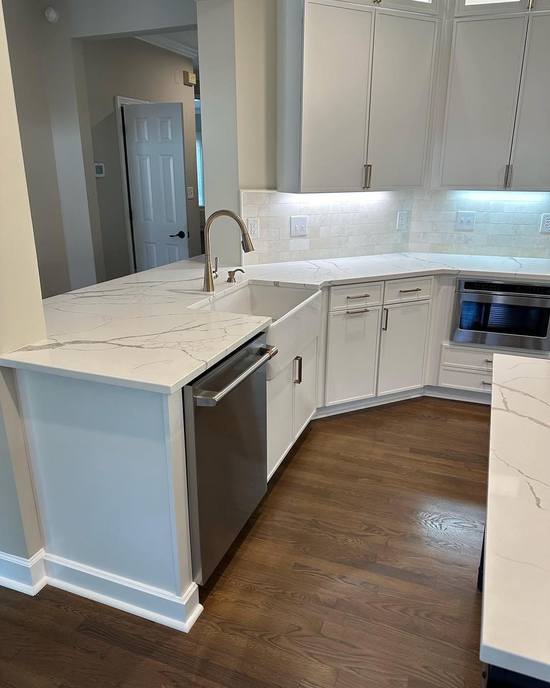Kitchen with white waterfall-edge stone island and stainless appliances fabricated by Prime Countertops